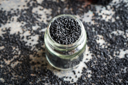 Glass jar full of black cumin or Nigella sativa seedsの写真素材