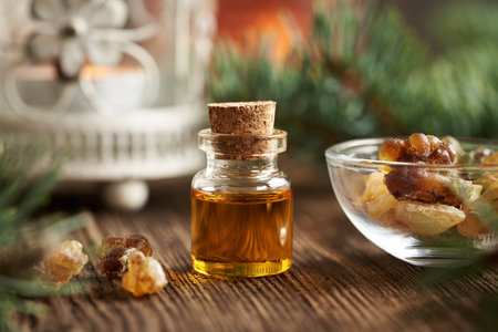 A bottle of frankincense essential oil with boswellia resin on a rustic wooden tableの写真素材