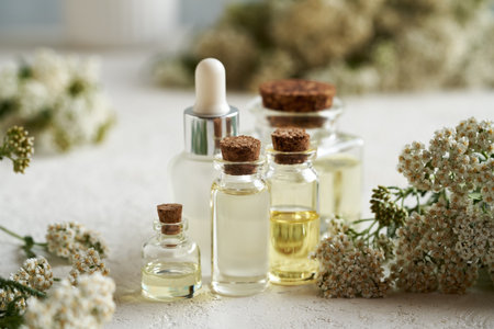 Bottles of aromatherapy essential oil with fresh yarrow flowers on bright backgroundの写真素材