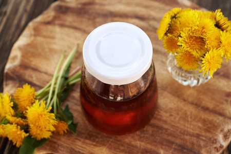 A glass jar of dandelion honey - syrup made from fresh Taraxacum flowersの写真素材