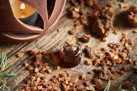 A transparent bottle of essential oil with myrrh resin and a candle at Christmasの写真素材