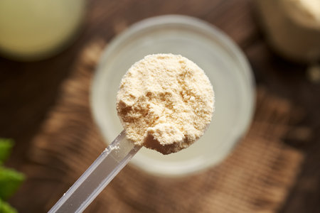 Whey protein powder in a measuring cup above a glass of drink, top viewの写真素材