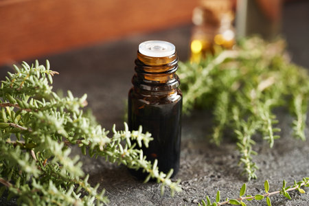 A dark bottle of aromatherapy essential oil with fresh thyme plantの写真素材