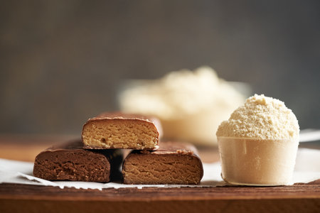 Healthy vegetarian protein chocolate bars with a scoop of whey protein powder, with copy space