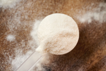 Collagen powder in a plastic measuring scoop on a wooden tableの写真素材