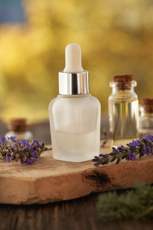 A bottle of aromatherapy essential oil with fresh purple lavender flowers outdoorsの写真素材