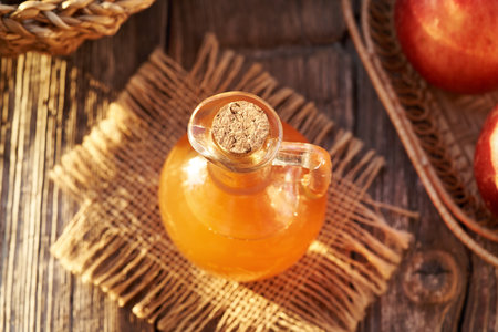 A jug of apple cider vinegar on a table in sunlightの写真素材