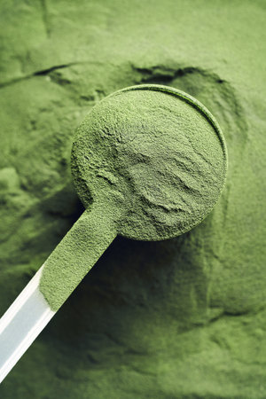 Green chlorella algae powder in a plastic measuring cupの写真素材