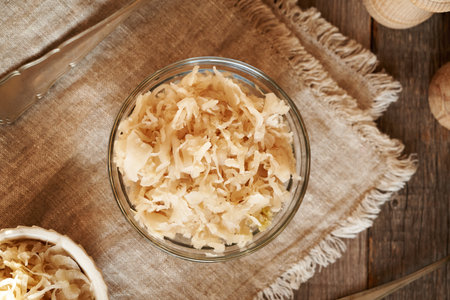 Homemade fermented cabbage or sauerkraut in a glass bowl on a table, top viewの写真素材