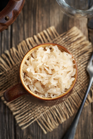 Homemade fermented cabbage or sauerkraut in a pot on a wooden table, top viewの写真素材