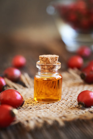 Rose hip seed oil in a glass bottle on a wooden tableの写真素材