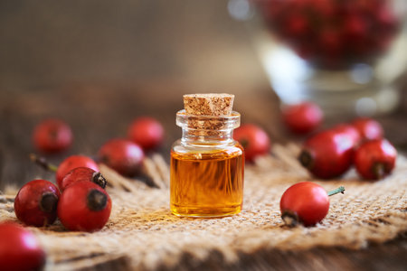 A glass bottle of rose hip seed oil with fresh rosehipsの写真素材