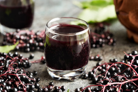 A cup of black elderberry syrup with fresh berriesの写真素材