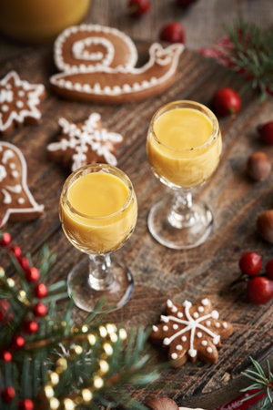 Two shot glasses with Christmas gingerbread cookies and decoration on a tableの写真素材