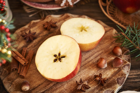 Halved red apple with a star in the middle with cinnamon, star anise and Christmas decorationの写真素材