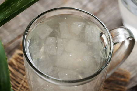 Fresh aloe vera pulp and juice in a glass cup with green leavesの写真素材