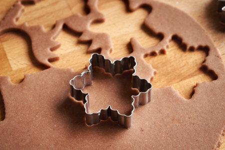 Cutting out star shapes from raw pastry dough - preparation of homemade gingerbread Christmas cookiesの写真素材