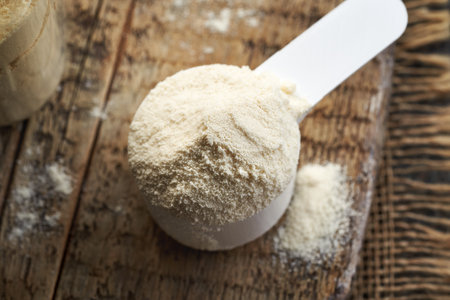 Whey protein powder in a white plastic measuring cupの写真素材