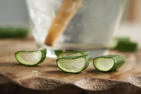 Slices of fresh aloe vera leaf with a glass of juice with ecological bamboo straw in the backgroundの写真素材