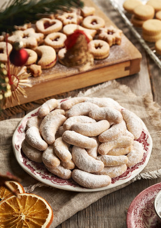 A plate of homemade Christmas cookies called Kipferl or vanilla crescents coated in sugar, with Linzer cookiesの写真素材