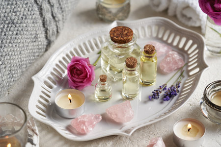 Several bottles of aromatherapy essential oil with lavender and rose flowers and rose quartz stonesの写真素材