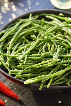 Fresh green Salicornia or Samphire seaweed in a bowl on a table with sesame seeds and chilli...