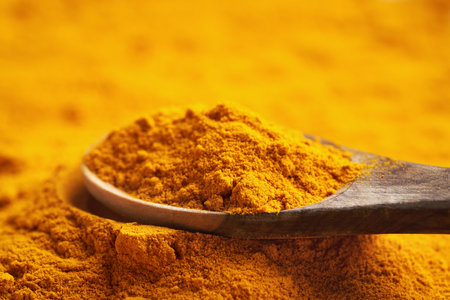 Close up of turmeric root powder on a wooden spoonの写真素材