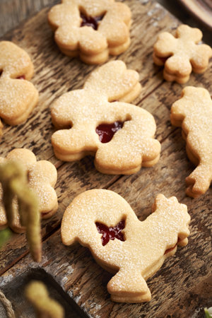 Linzer cookie in the shape of Easter bunny and rooster filled with strawberry marmalade and dusted...