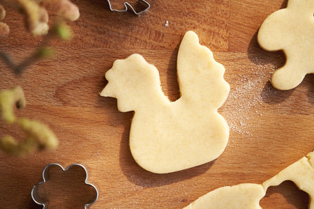 Cutting out hen shapes from raw pastry dough - preparation of homemade Linzer Easter cookies, top viewの写真素材