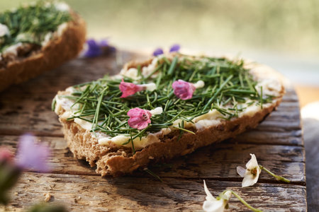Spring wild edible plant called onion grass or crow garlic on a slice of bread, with edible lungwort flowersの写真素材
