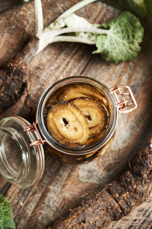 Preparation of homemade herbal tincture from fresh burdock root and alcohol in a glass jar, top viewの写真素材