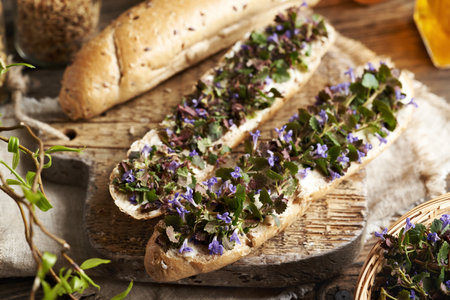 Fresh ground-ivy flowers and leaves collected in spring on slices of bread on a wooden table