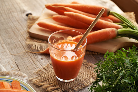 A glass of fresh carrot juice on a wooden tableの写真素材