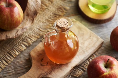 Apple cider vinegar in a glass bottle on a tableの写真素材