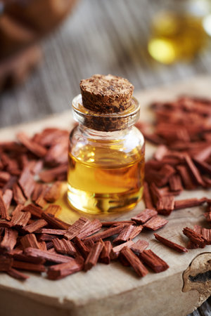 Aromatherapy essential oil in a glass bottle with red sandalwood chipsの写真素材