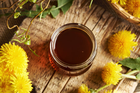 Dandelion honey in a glass jar on a wooden table, top viewの写真素材