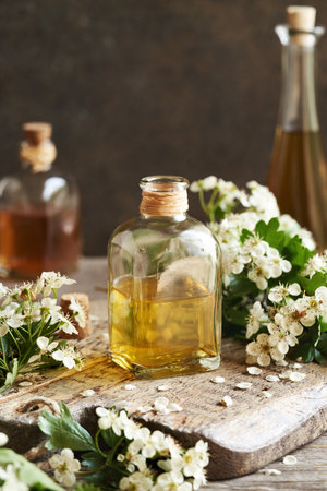 A bottle of herbal tincture with fresh hawthorn flowers on a table in springの写真素材
