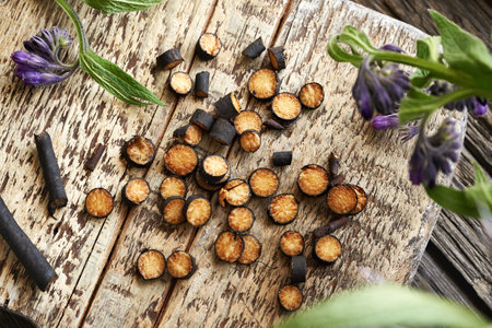 Cut up fresh comfrey or knitbone root on a wooden board - ingredient for herbal tinctureの写真素材