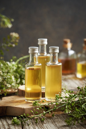 Bottles of herbal tincture made of fresh blooming shepherd's purse plant on a wooden tableの写真素材