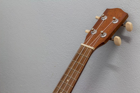 Close up of ukulele on white wall.