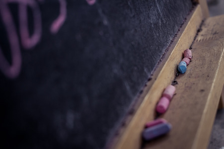 Pieces of school chalk on old black chalkboard. Selective focus,vintage style.の写真素材