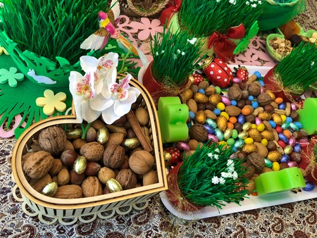 Novruz setting table decoration, tea in tulip shape glass on ethnic motives rustic table cloth with wheat grass, dyed eggs, traditional sweets, samovar, new year sring celebration, nature awakening orchids birds macrons nutsの写真素材