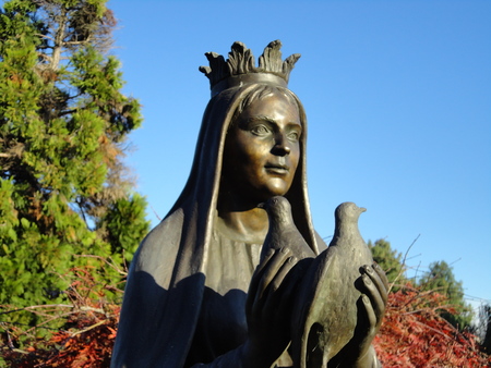 Bronze sculpture of a lady. She holds two doves on floreal and celestial backgroundの写真素材