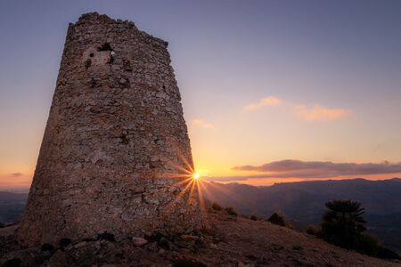 Watchtower at sunset with sun flare, located between Cala Agulla and Cala Mesquida, Mallorca, Spain.