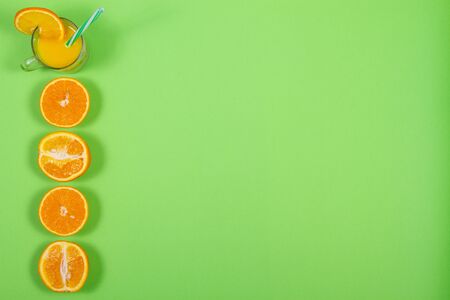 top view on glass of fresh orange juice on green background with place for textの写真素材