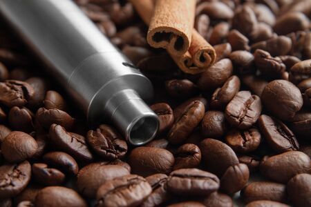Concept of Coffee and canella E-Juice Flavor with copy space.  Vape Pen Kit and cinnamon lies on the background of Soft focused coffee beans.の写真素材