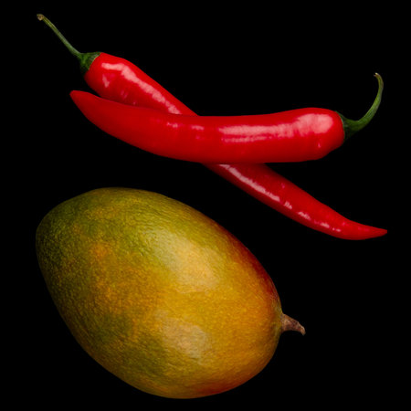 Whole mangoe and chili on black background. Ingredients for Spicy mango chutney.の写真素材