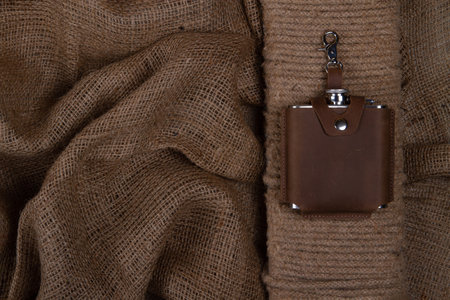 Hip flask in leather Hip flask case on sack cloth backgroundの写真素材