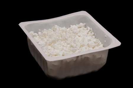 Cottage cheese in container isolated on black background. European style curd. side viewの写真素材