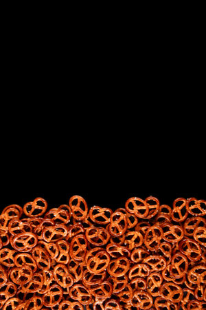 Border of mini pretzels on black background. Dark backdrop with Salted snacksの写真素材